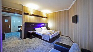 A hotel room with a large bed, bedside tables, a TV, and a carpeted floor. - Astoria Tbilisi (Tbilisi)