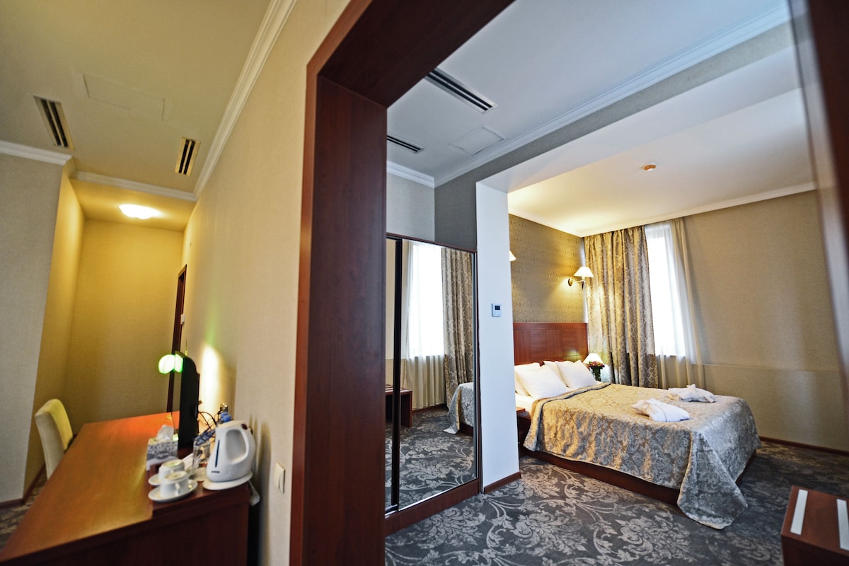 Habitación de hotel con cama, escritorio con lámpara, silla y espejo.
