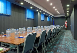 A conference room with a long table, chairs, water bottles, and flags. - Astoria Tbilisi (Tbilisi)