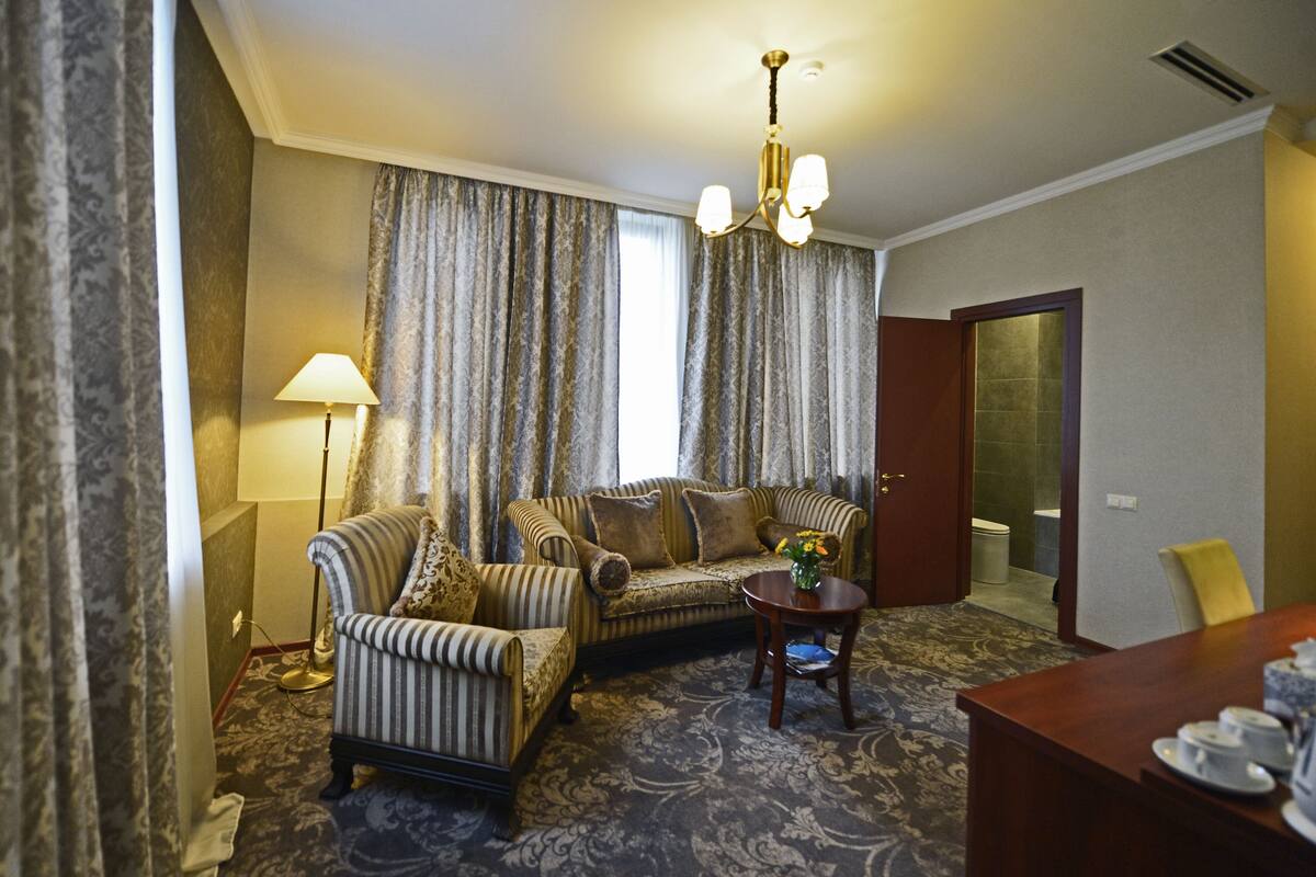 Ein Hotelzimmer mit einer Couch, einem Sessel und einem kleinen Tisch mit Blumenvase.