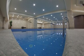 Una piscina interior con agua cristalina, rodeada de paredes con un diseño de azulejos.