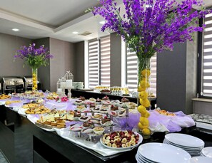 A buffet setup with various food items and decorative flowers. - Astoria Tbilisi (Tbilisi)