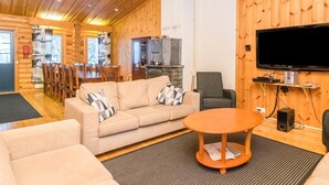 A cozy log cabin interior with a sofa, armchair, dining table, and a fireplace. - Karhunpesä a by Interhome (Puolanka)