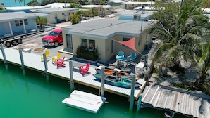 A waterfront property with a dock, a red truck, and several colorful chairs. - Oceanside, Pet Friendly, Smart Home with-SUP, kayak with and 60 ft Dock (Marathon)