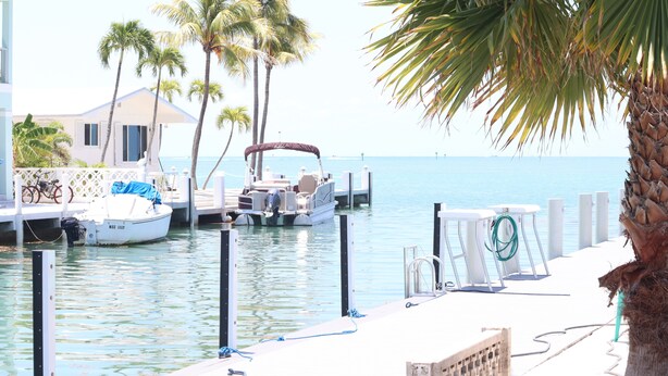 A marina with boats docked, a house with a balcony, and palm trees. - Oceanside, Pet Friendly, Smart Home with-SUP, kayak with and 60 ft Dock (Marathon)
