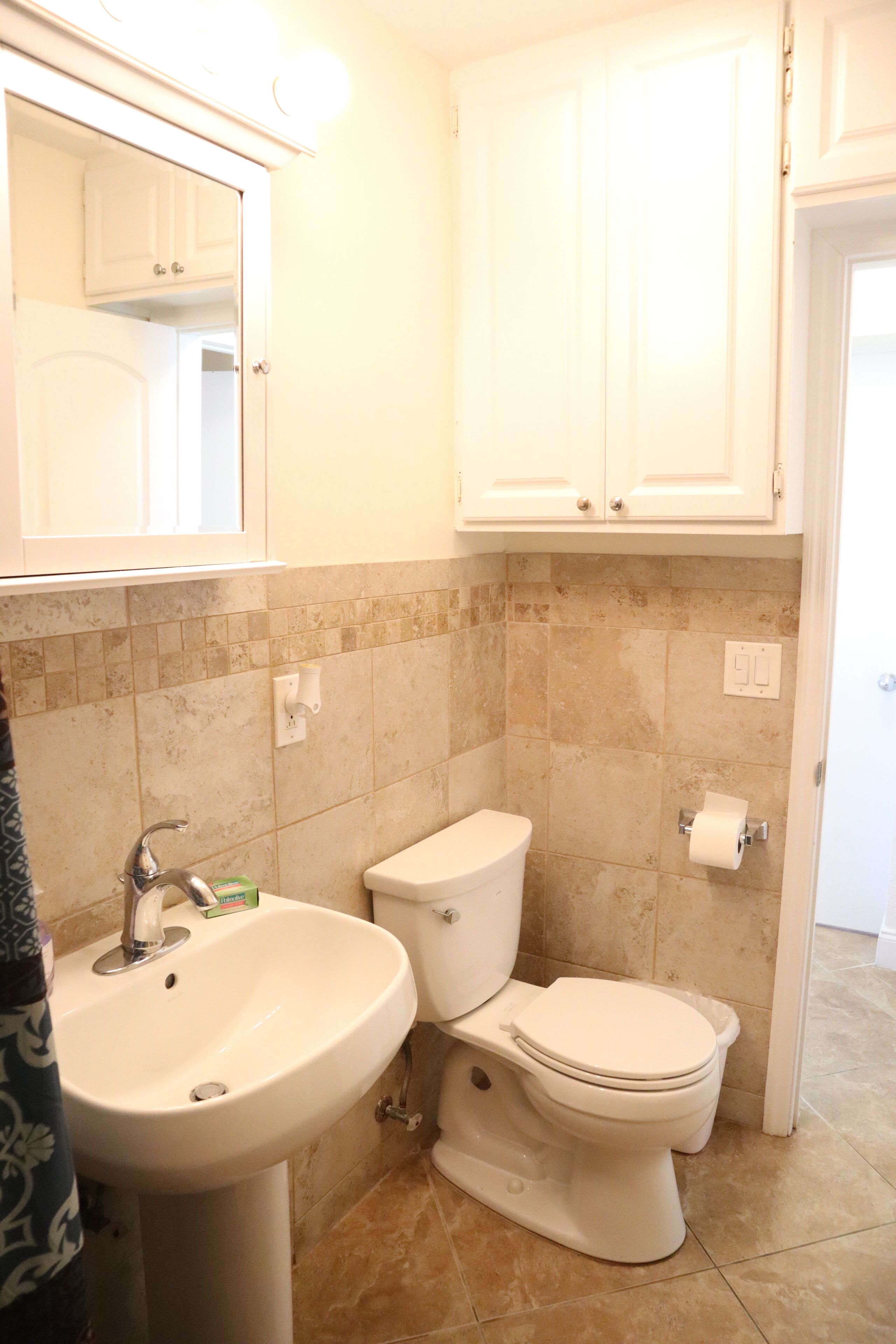 A bathroom with a sink, toilet, and cabinets.