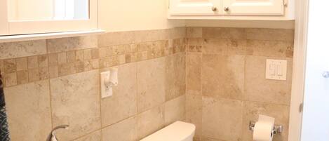 A bathroom with a sink, toilet, and cabinets.