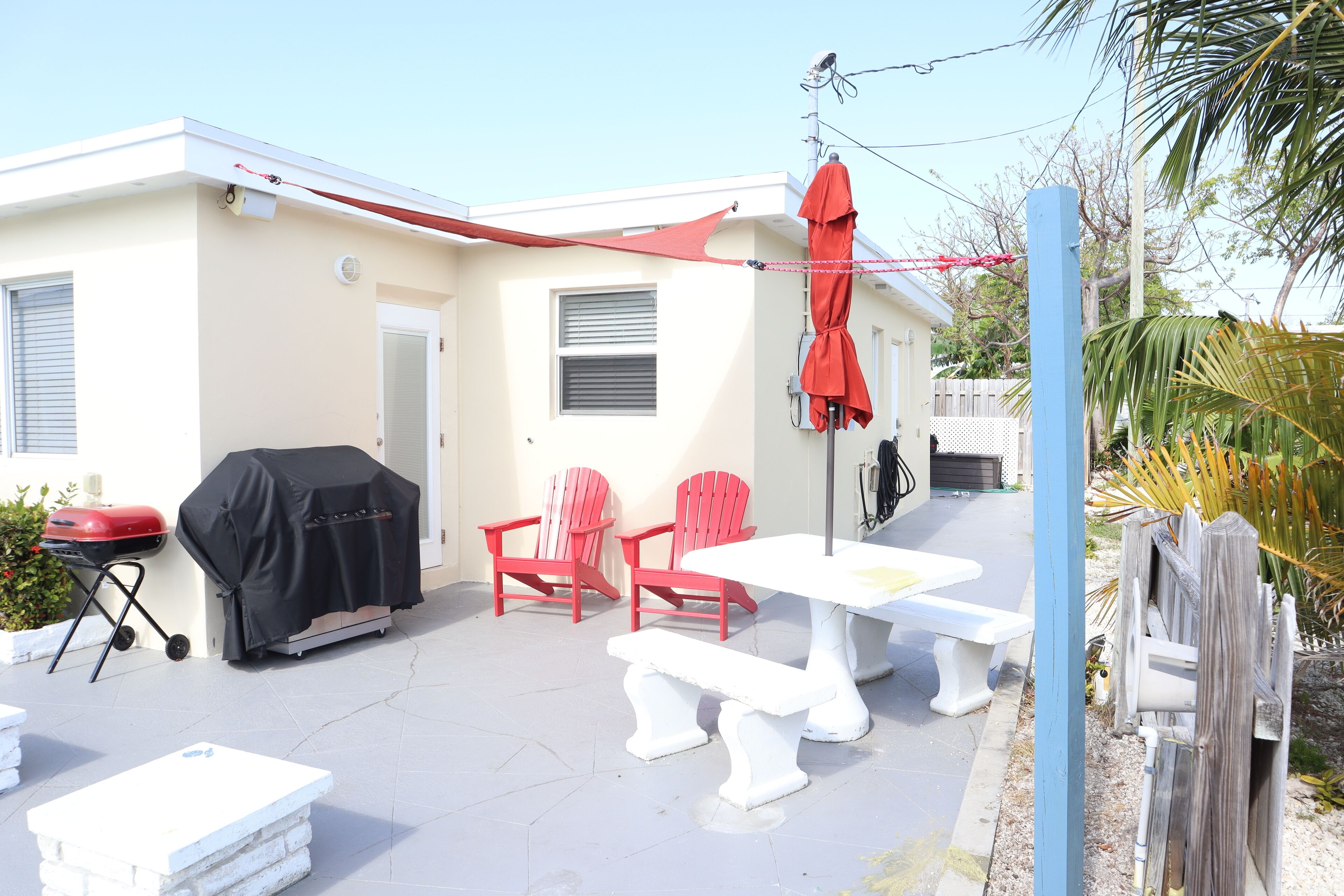 A patio area with a table and chairs, a barbecue grill, and a covered umbrella.