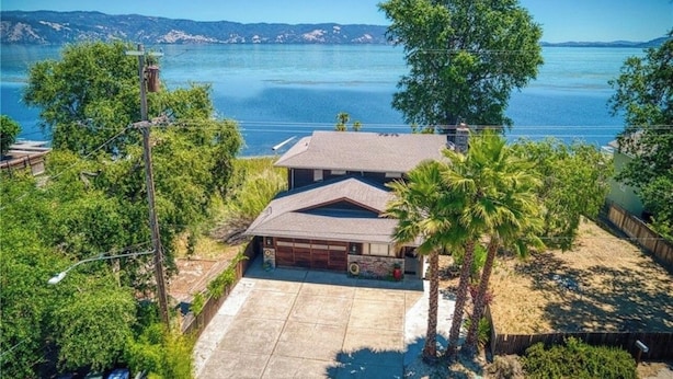 Ein Haus mit Garage, umgeben von Bäumen und Blick auf ein großes Gewässer.
