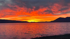 Ein Sonnenuntergang über einem ruhigen See, im Hintergrund Berge.