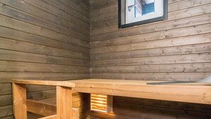 A wooden cabin interior with a wooden bench and a framed picture on the wall. - Skivillas paljakka 6. (2mh) by Interhome (Puolanka)