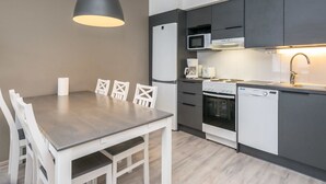 A modern kitchen with a dining table, chairs, a refrigerator, microwave, coffee maker, stove, and dishwasher. - Skivillas paljakka 6. (2mh) by Interhome (Puolanka)