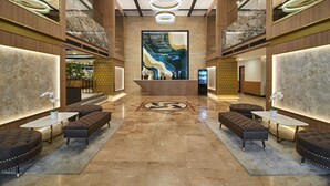 A spacious lobby with a central reception desk, multiple seating areas, and a large abstract artwork on the wall. - IDEAS Kuala Lumpur (Kuala Lumpur)