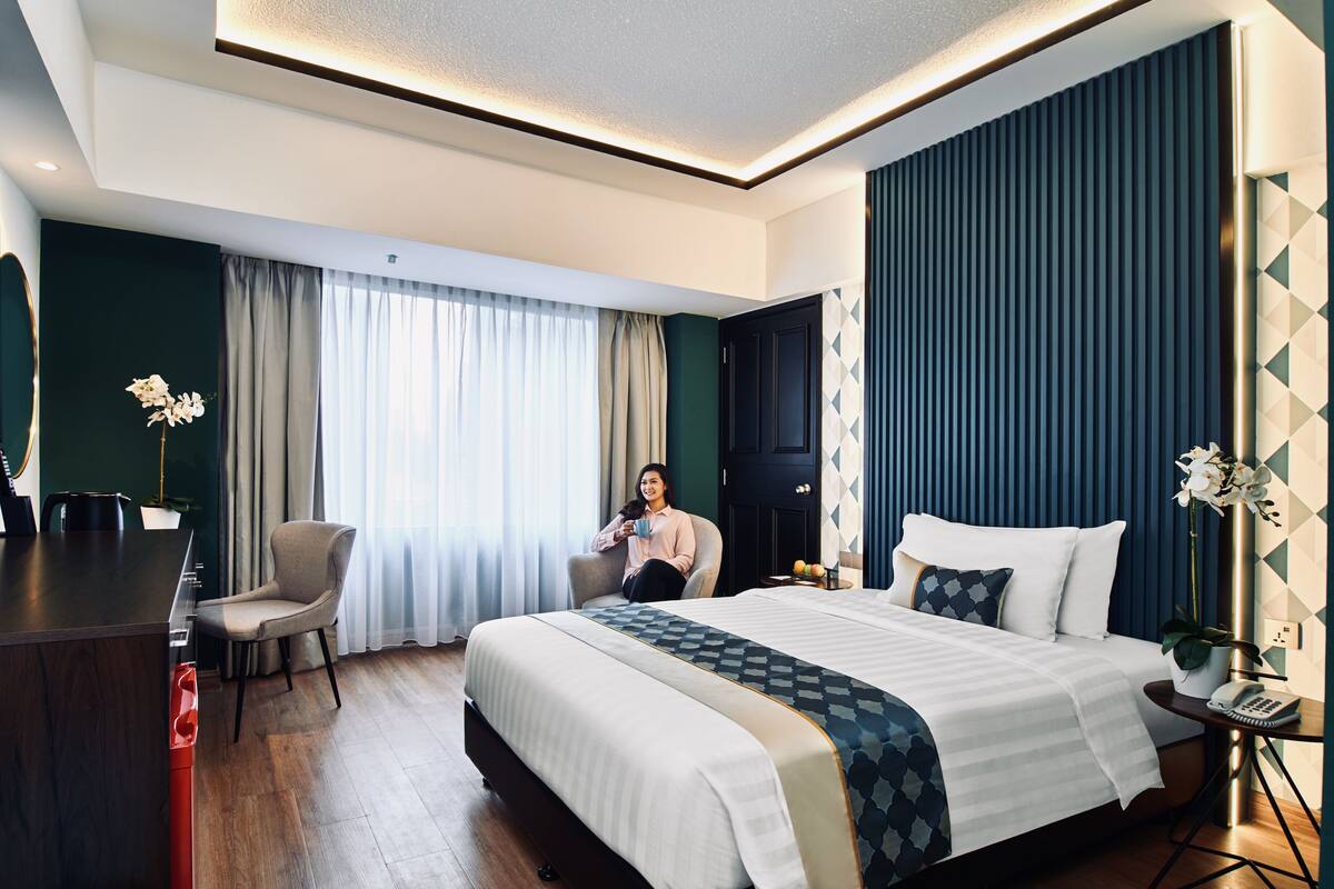 A modern hotel room with a large bed, a desk, and a chair.