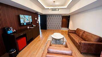 A modern living room with a wooden floor, a brown sofa, a white coffee table, and a TV on a wooden wall.