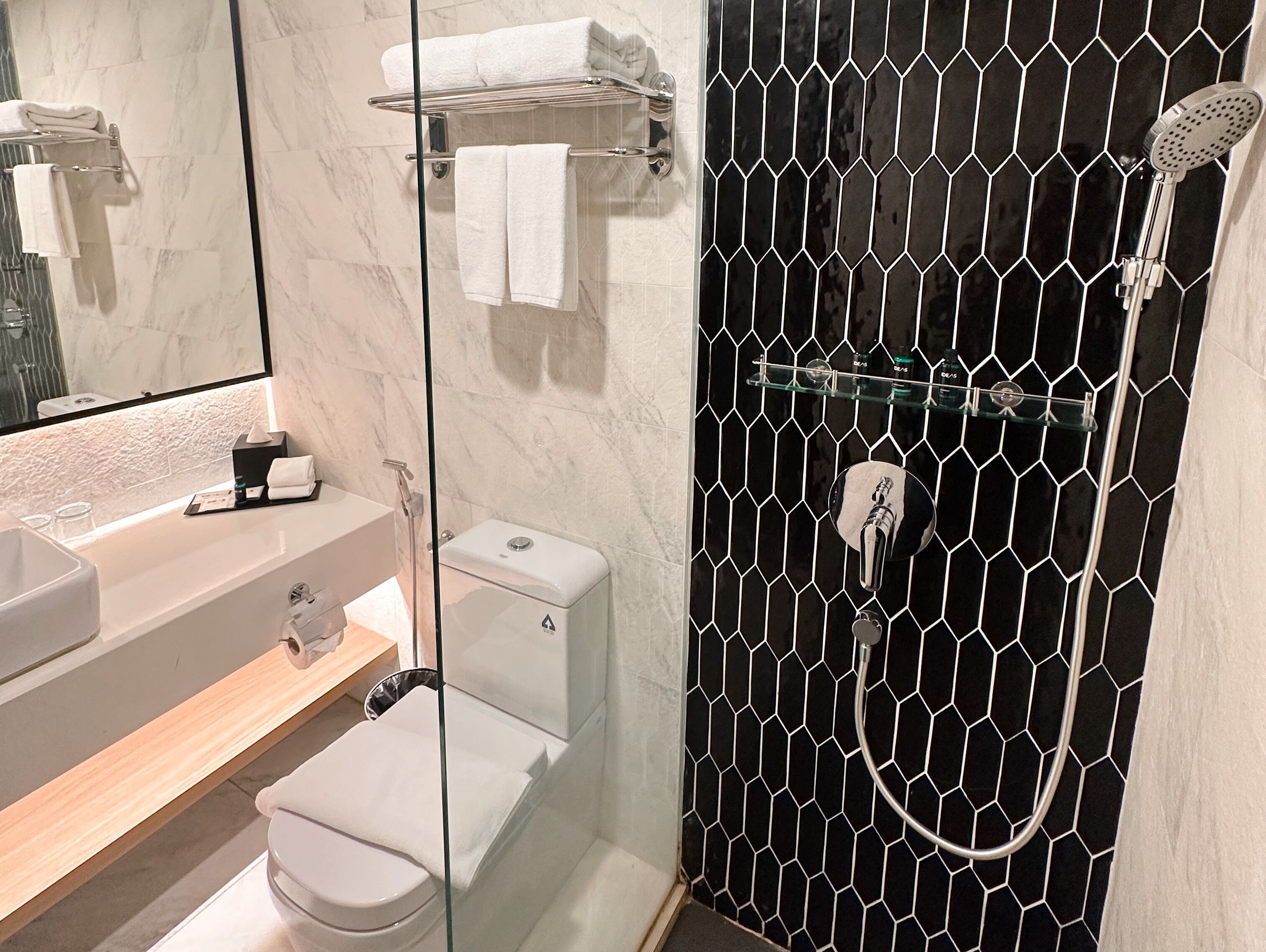 A modern bathroom with a glass shower enclosure, a white toilet, and a vanity with a mirror.
