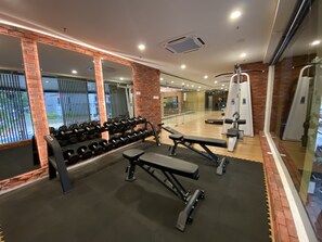 A gym with weight benches, dumbbells, and exercise machines.