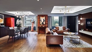 A modern living room with a sofa, coffee table, and dining area. There is a large window providing natural light and a view of the city. - IDEAS Kuala Lumpur (Kuala Lumpur)