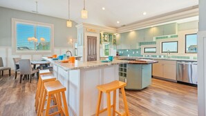 Una cocina moderna con una isla central, taburetes de bar y un área de comedor con vistas.