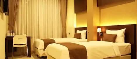 Une chambre d’hôtel avec deux lits, un bureau et une chaise.