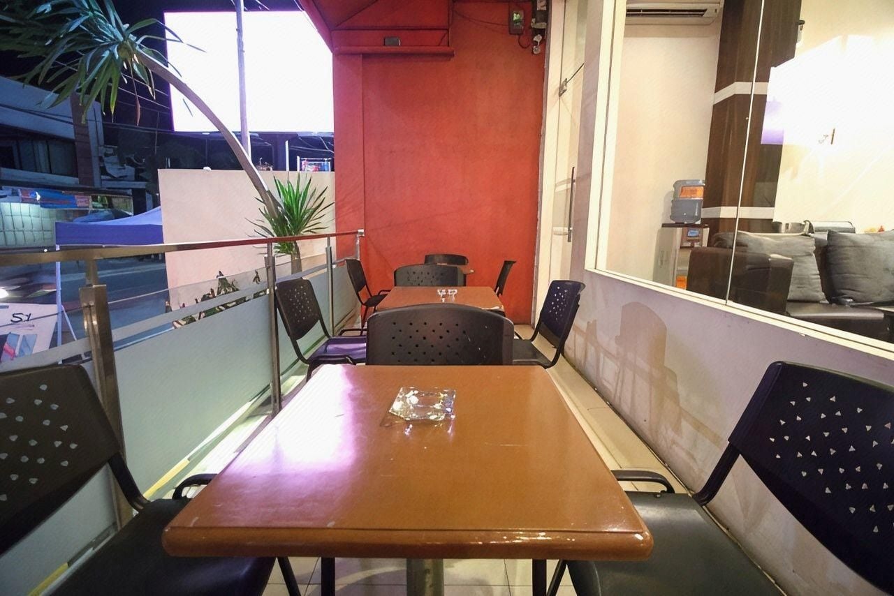 A dining area with a table and chairs, a potted plant, and a view of the street.