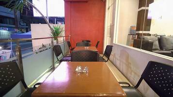 A dining area with a table and chairs, a potted plant, and a view of the street.