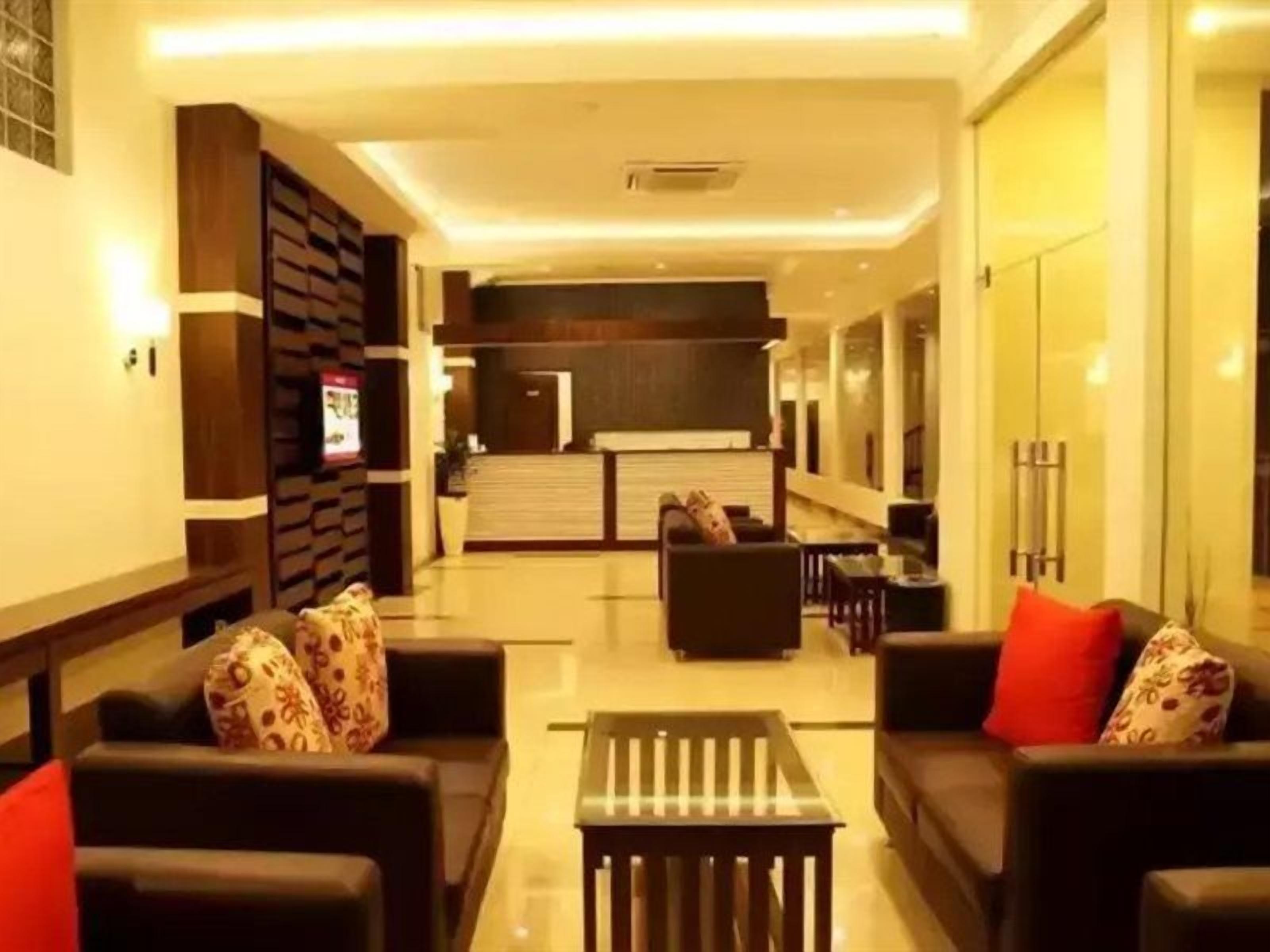 Un moderno vestíbulo de hotel con un mostrador de recepción, área de estar y una pared de vidrio.
