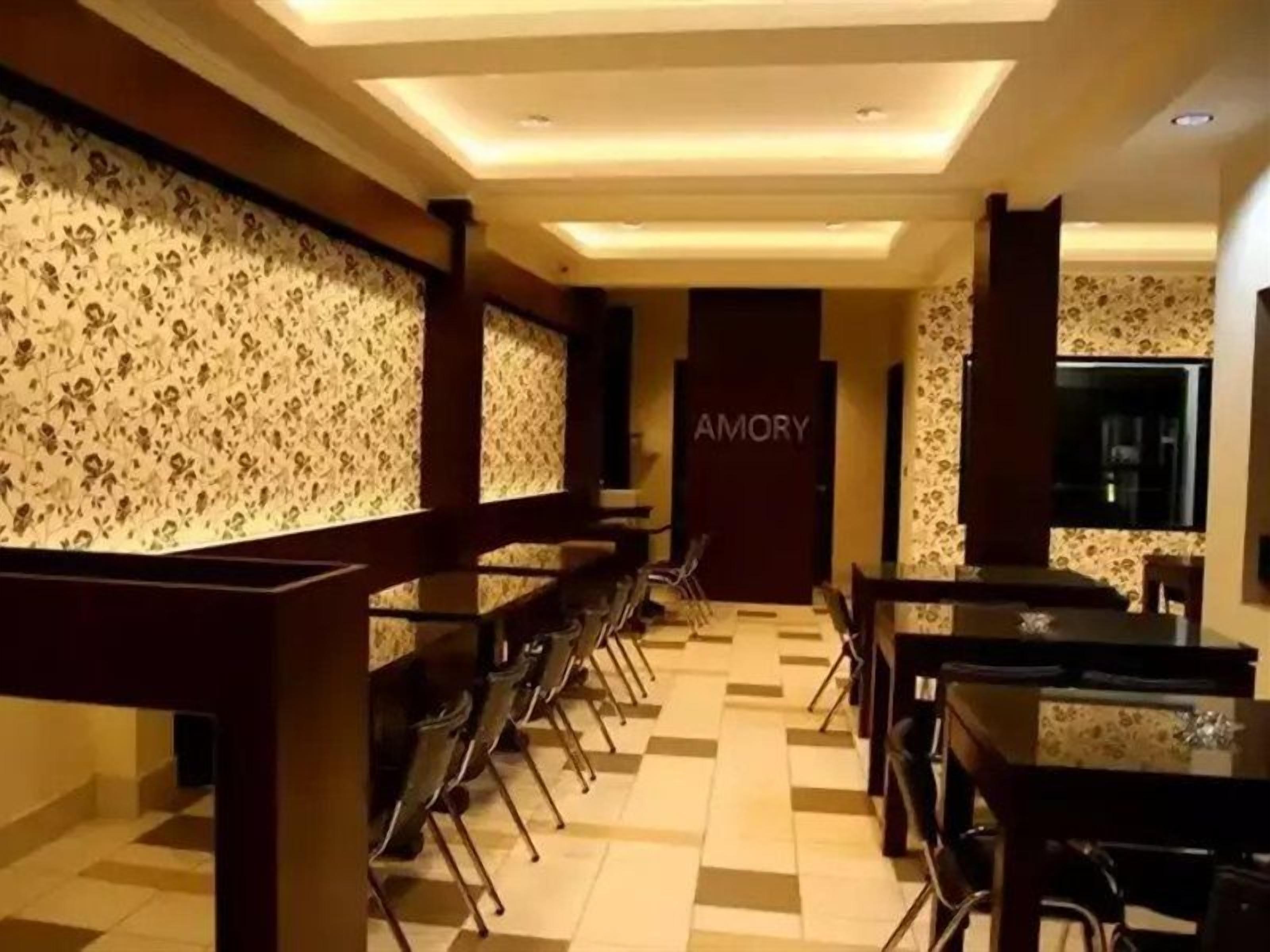 A hotel dining area with a long counter, multiple tables, and chairs.