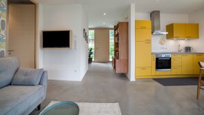 Een moderne keuken met gele kastjes, een ingebouwde oven en een flatscreen televisie aan de muur.
