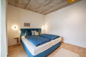 A bedroom with a bed, bedside tables, a headboard, a wall-mounted light, and a wooden floor. - Holiday Apartment "Das Eckige" with Mountain View, Wi-Fi, Garden & Terrace (Tscherms)