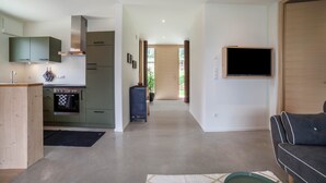 Une cuisine moderne dotée d’appareils électroménagers intégrés, un coin repas avec un canapé et un téléviseur fixé au mur.