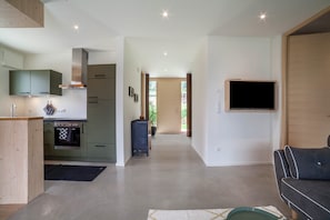 A modern kitchen with built-in appliances, a dining area with a sofa, and a TV mounted on the wall. - Holiday Apartment "Das Runde" with Mountain View, Wi-Fi, Garden & Terrace (Tscherms)