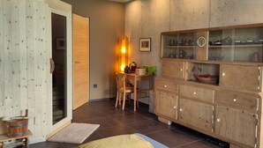 Une pièce avec un meuble en bois, une table avec des chaises et une porte en bois.