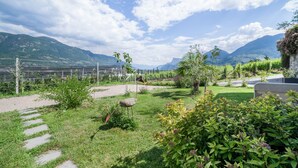 A garden with a stone path, a metal sculpture, and a bench. - Holiday Apartment Vitus with Mountain View, Wi-Fi, Garden & Terrace (Tscherms)