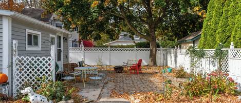 A residential backyard with a patio, a dog statue, and a white fence.