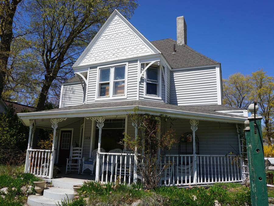 A two-story house with a porch and a chimney.