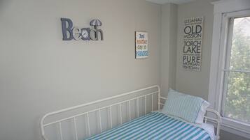 A bedroom with a bed, a window, and wall decorations including a clock and a sign with text.