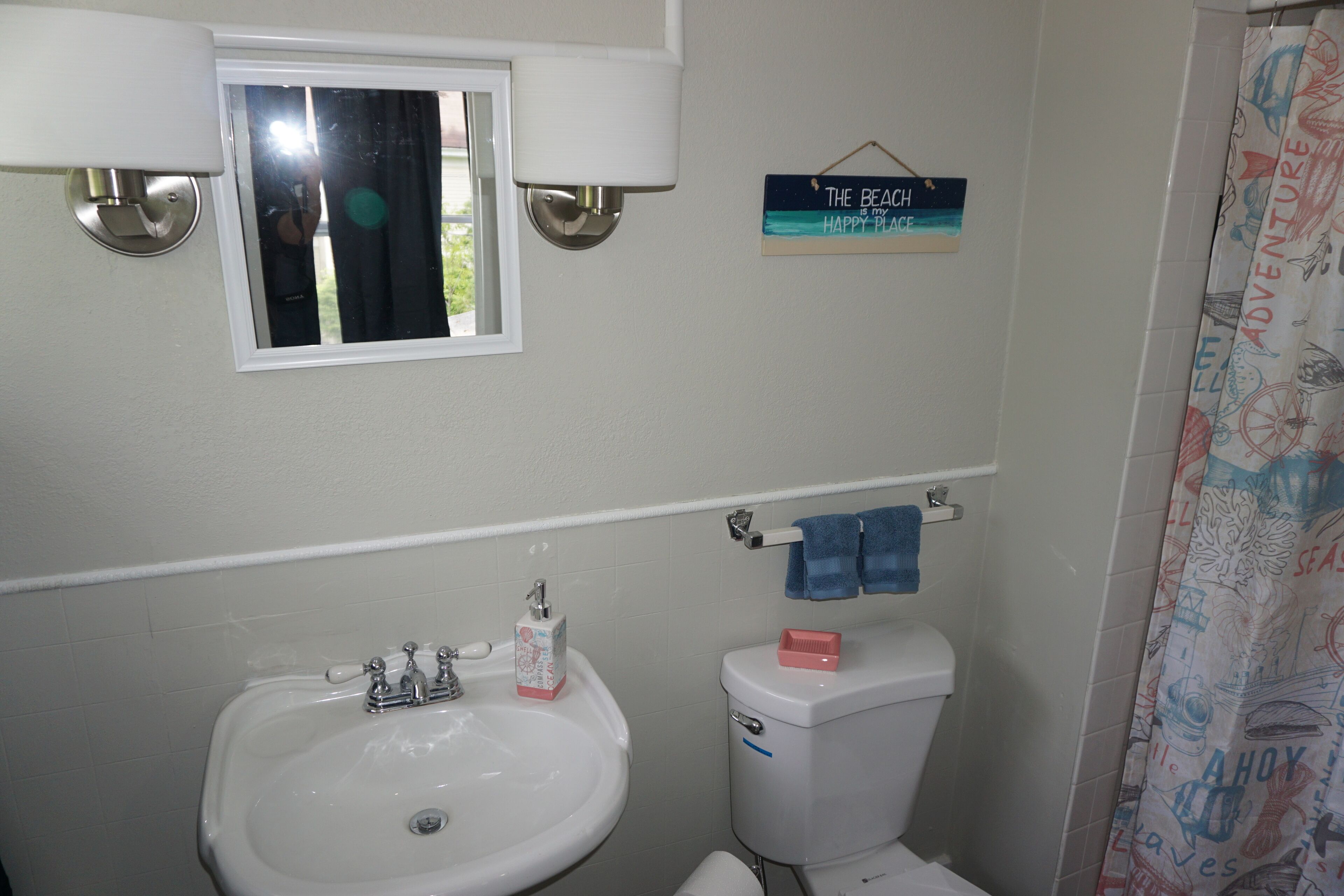 A bathroom with a sink, toilet, and a window.