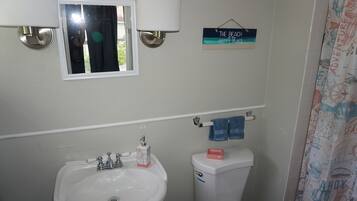 Une salle de bain avec un lavabo, des toilettes et une fenêtre.