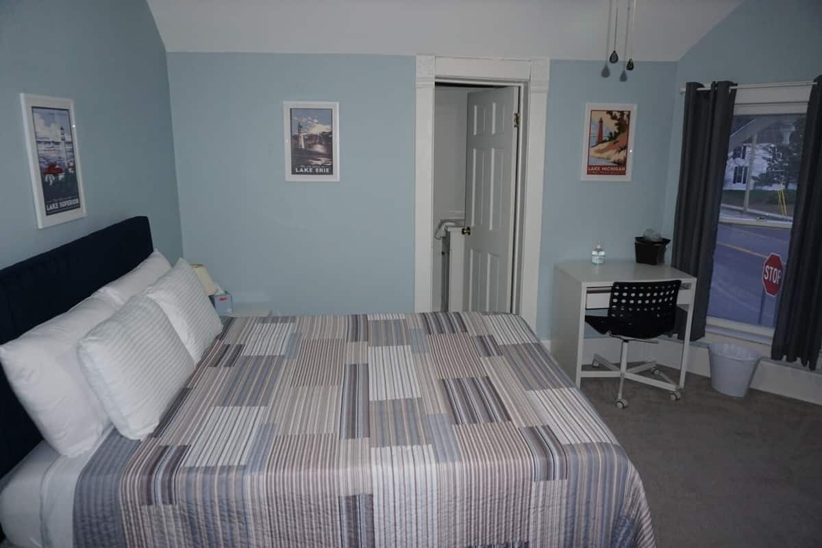 A bedroom with a bed, a desk, and posters on the wall.
