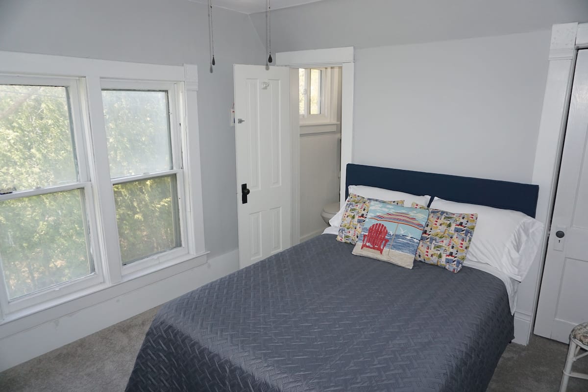 A bedroom with a bed, a window, and a door.