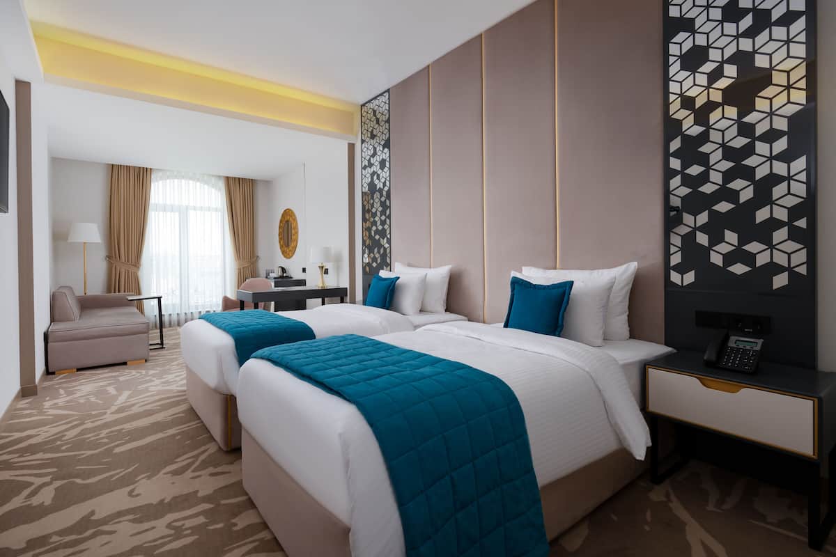 A hotel room with two beds, a desk, a chair, a TV, and a phone on the nightstand.
