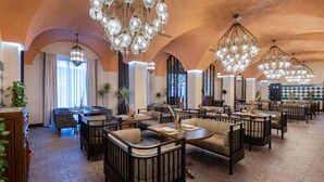 A spacious restaurant with high ceilings, ornate chandeliers, and a variety of seating arrangements including booths and tables. - Mercure Tashkent South (Tashkent)