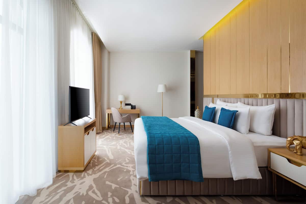 A hotel room with a bed, a desk, a TV, and a chair.