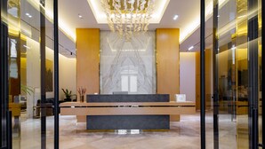 A reception area with a marble wall, wooden paneling, and a modern chandelier. - Mercure Tashkent South (Tashkent)