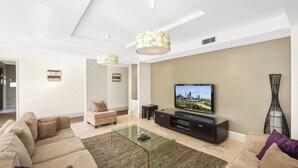 A modern living room with a sofa, coffee table, TV, and decorative items.