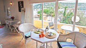 Ein Balkon mit Tisch für zwei Personen, Stühlen und Blick auf die Stadt, sowie einer Tür zum Innenbereich.
