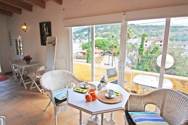 Un balcon avec une table dressée pour deux personnes, des chaises, une vue sur la ville et une porte donnant sur l’intérieur.