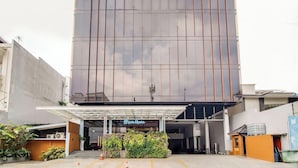 Un hôtel moderne doté d’une grande façade en verre, d’une entrée couverte et d’une enseigne indiquant « Motel Home ».