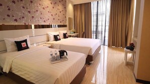 Une chambre d’hôtel avec deux lits, une table de chevet, une chaise, une grande fenêtre avec des rideaux et un papier peint à motifs floraux.
